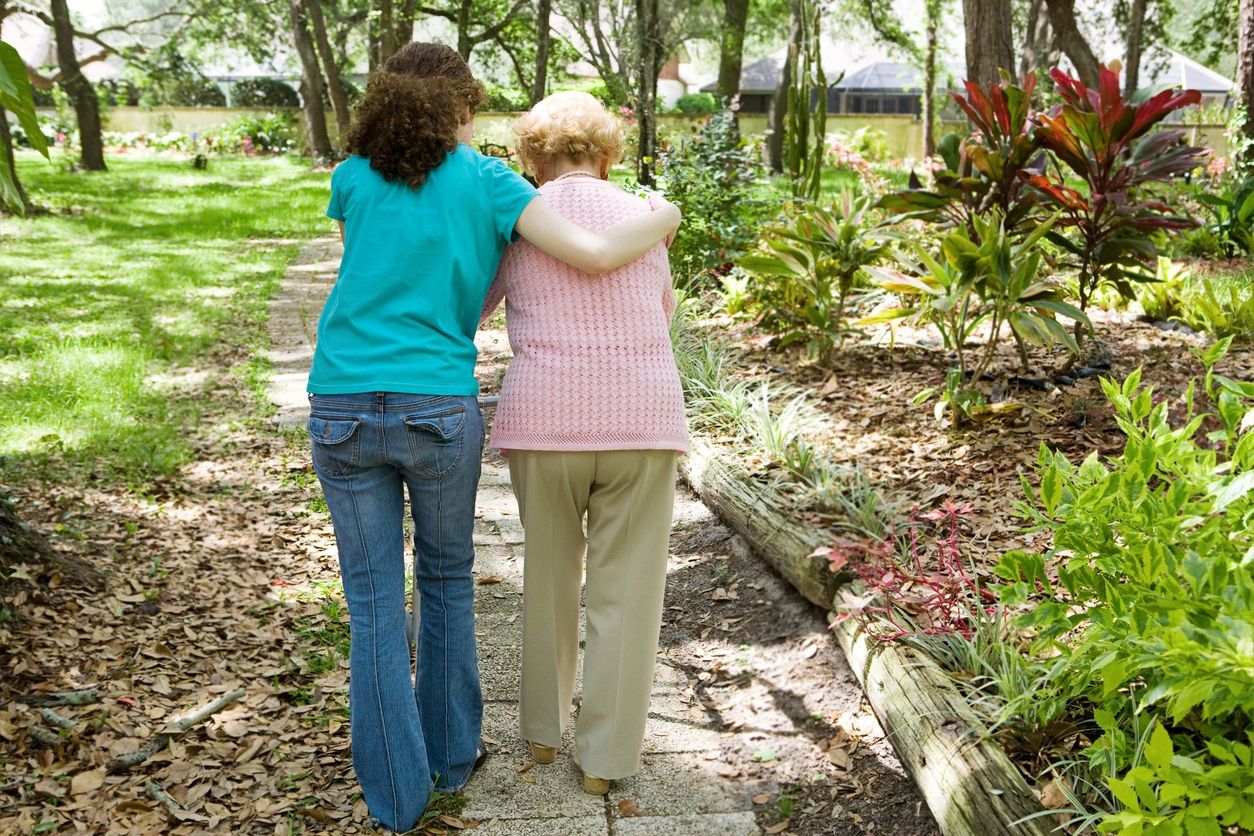 Two women are walking arm in arm through a park.