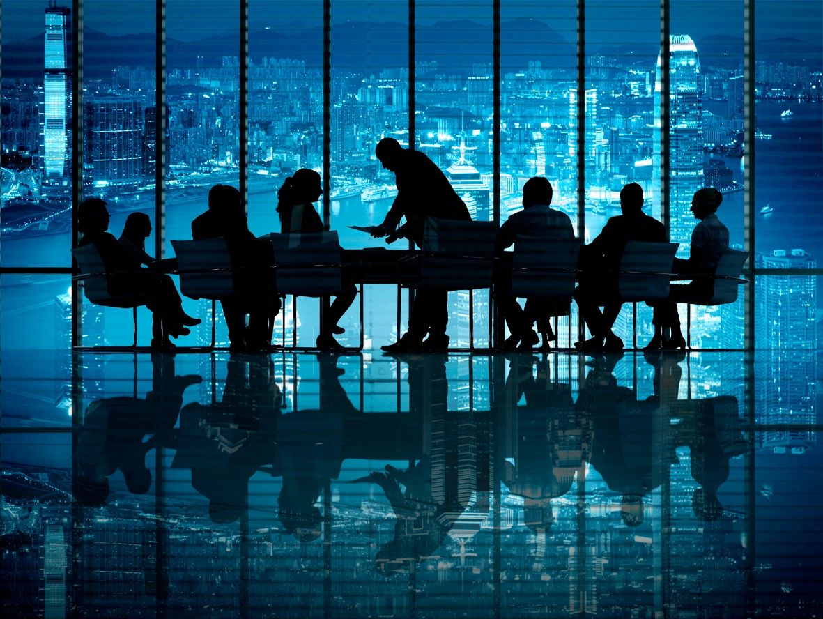 A group of people sitting at a table in front of a window.